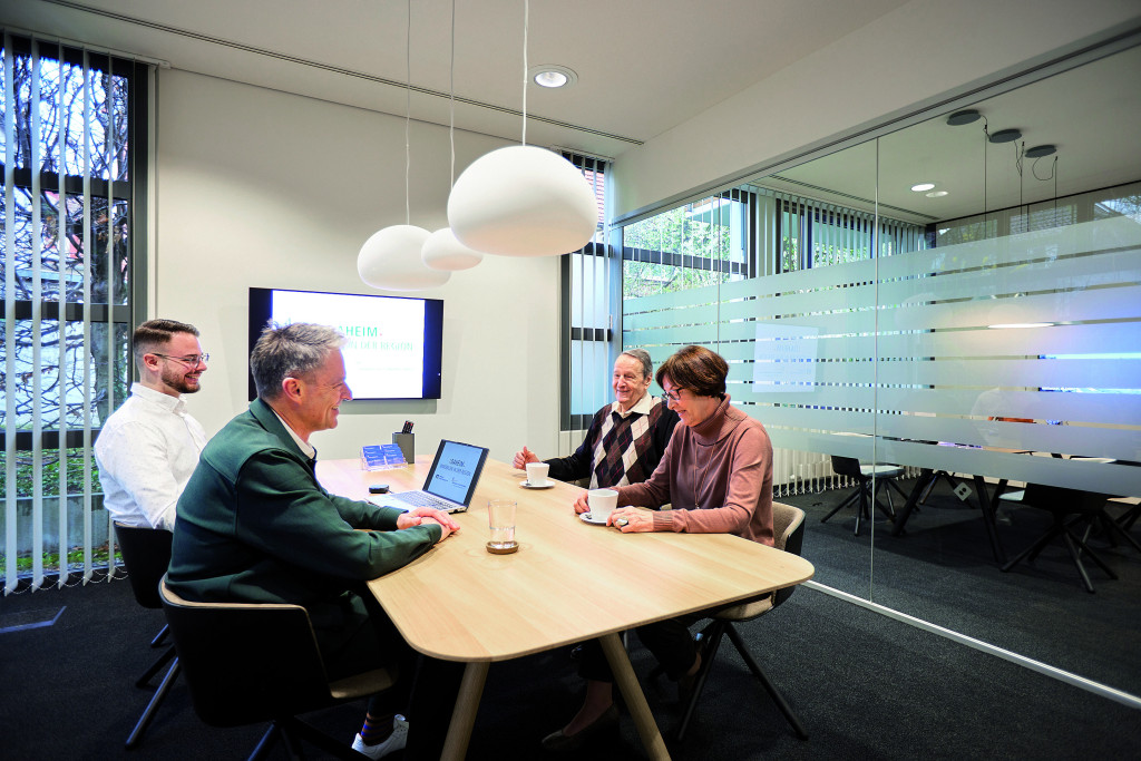 Roland Kessel und Mirko Traballano beraten einen älteren Herren und seine Tochter zum Thema Immobilien.